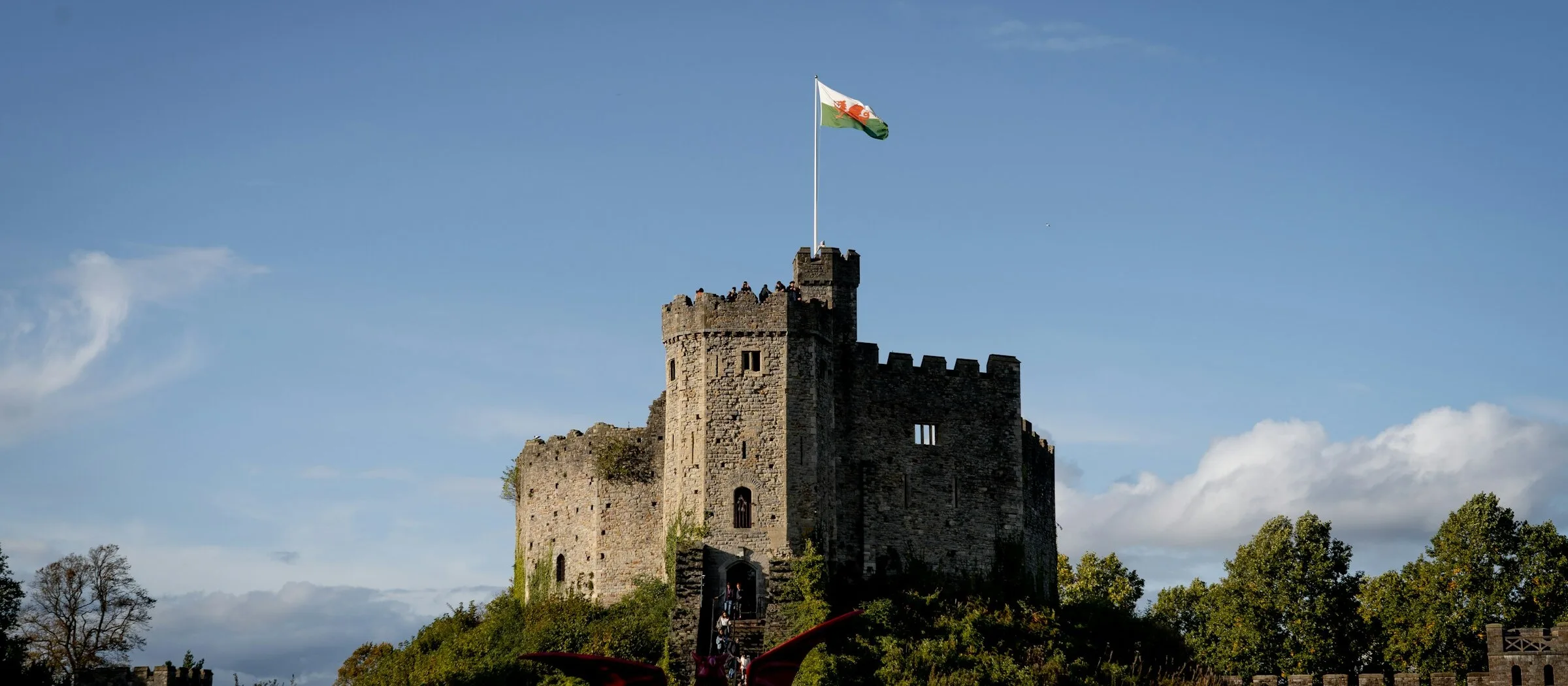 The keep at Cardiff Castle in late afternoon sun with the Welsh flag flying from the tower