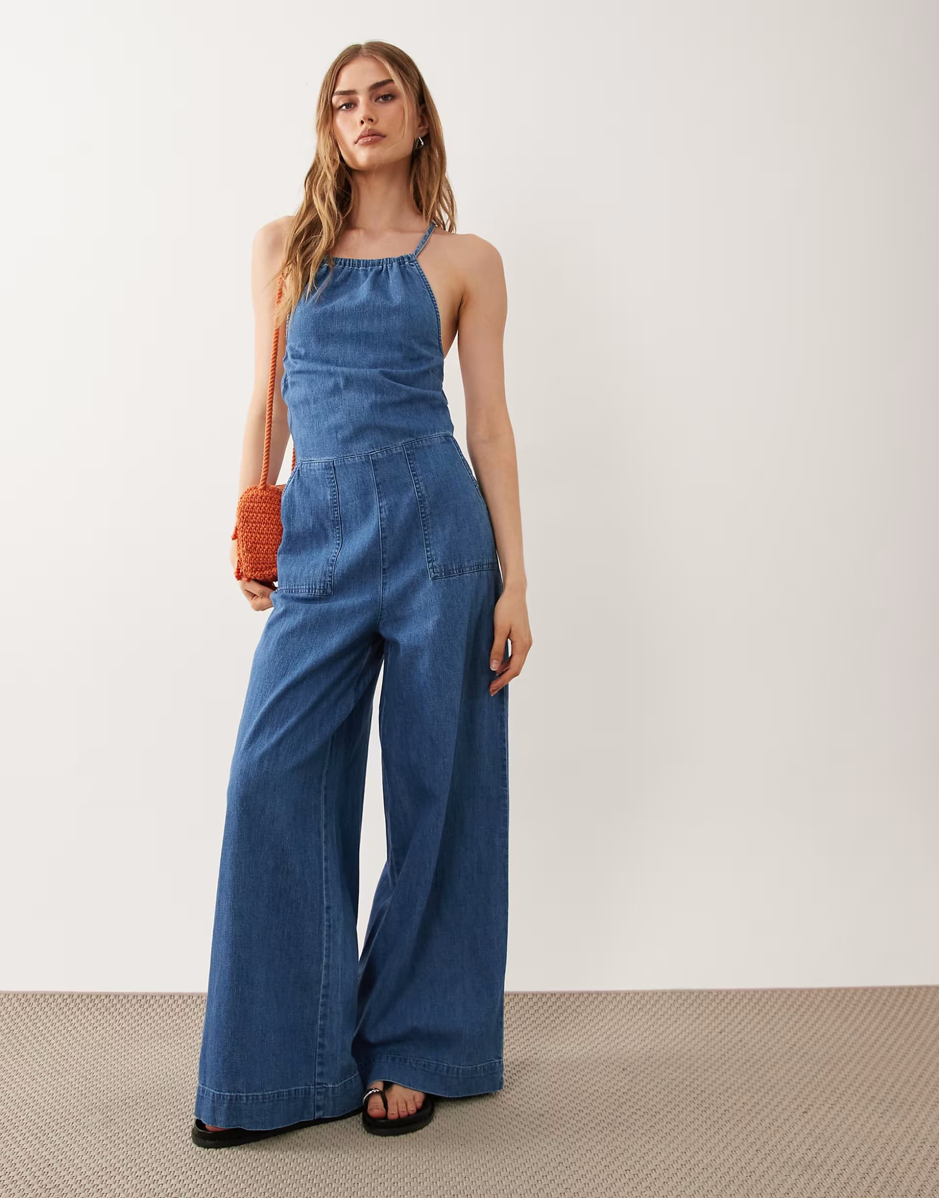 ASOS ASOS DESIGN halter neck denim jumpsuit with patch pockets in midwash